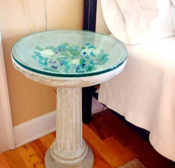 A bird bath table displays colorful seaglass